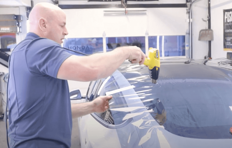 shop worker putting window tint on a Tesla Model 3