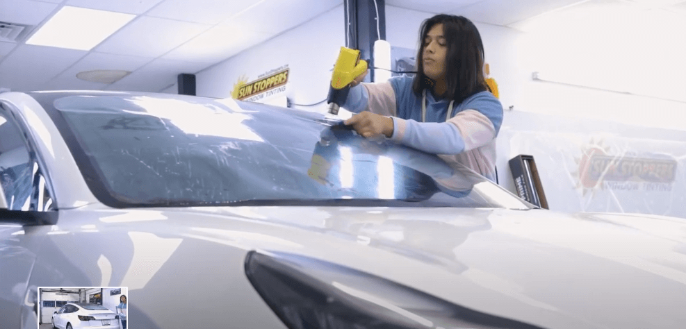 A Sun Stoppers Technician smoothes out window tint film on a Tesla