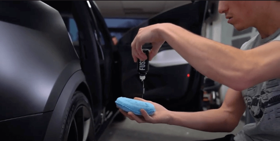 a Sun Stoppers worker putting ceramic coating on a Tesla