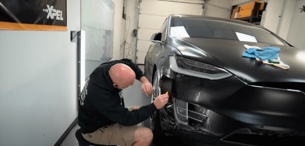 Sun Stoppers worker putting paint protection on a Tesla car