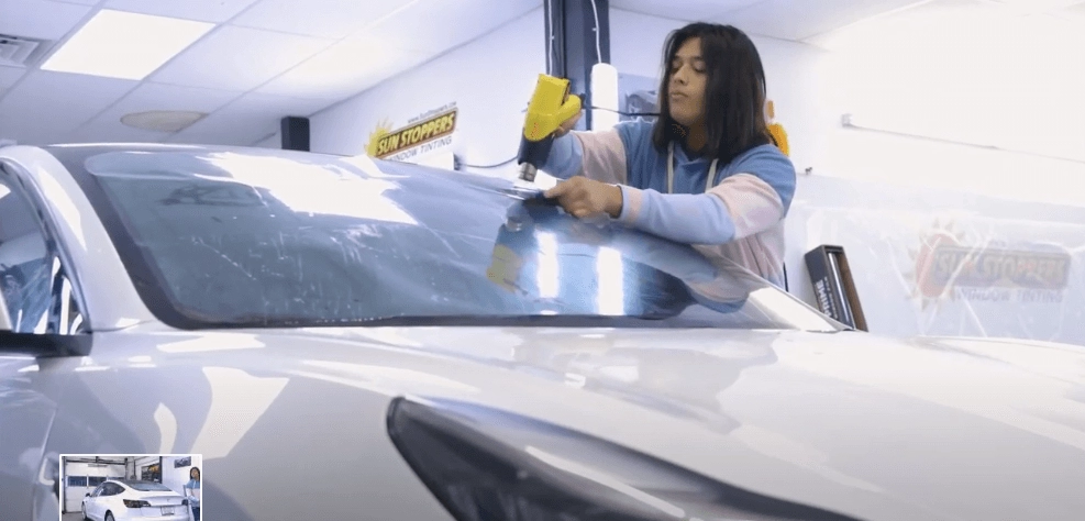A Sun Stoppers Technician smoothes out window tint film on a Tesla