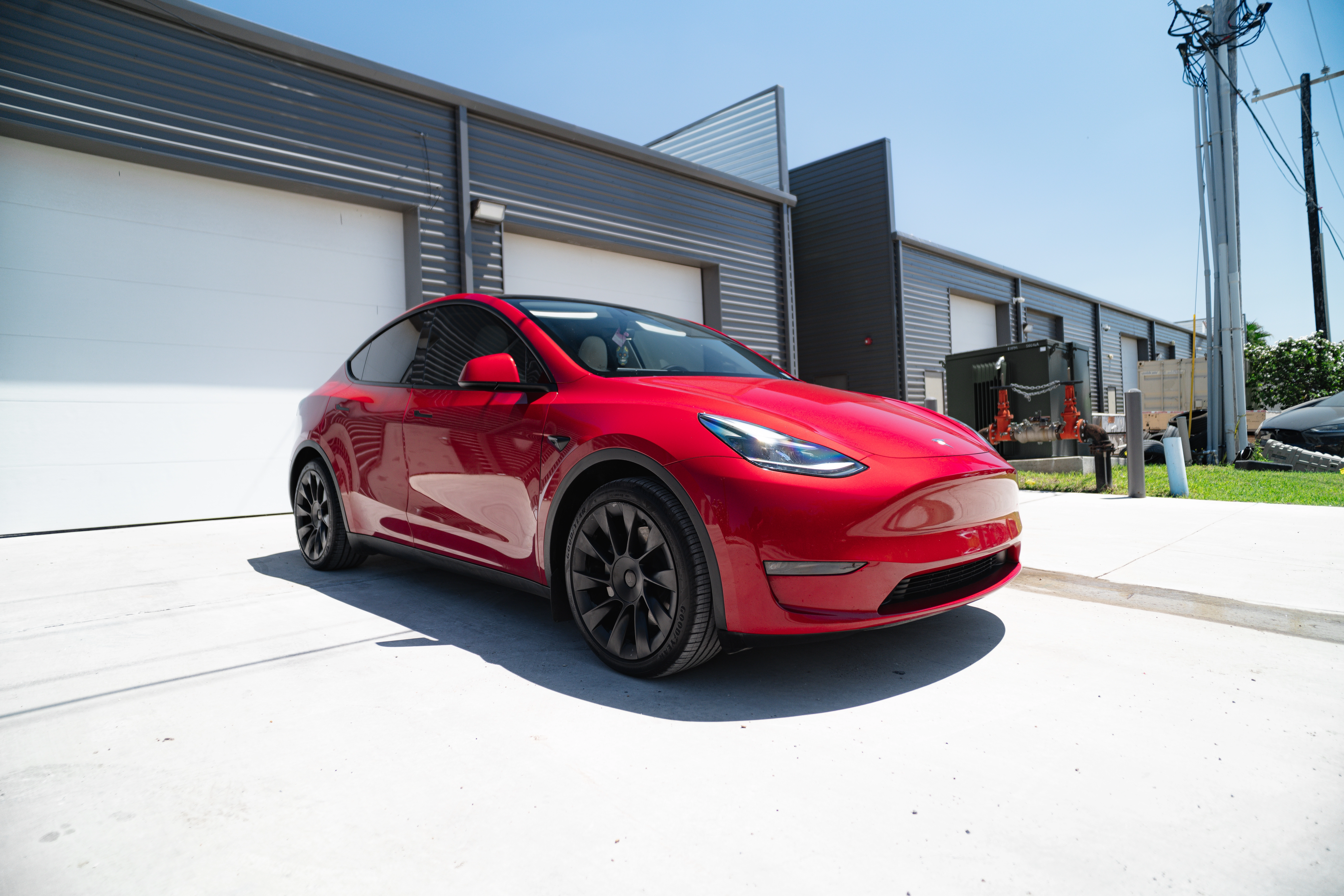 Red Tesla Model Y parked outside a modern garage