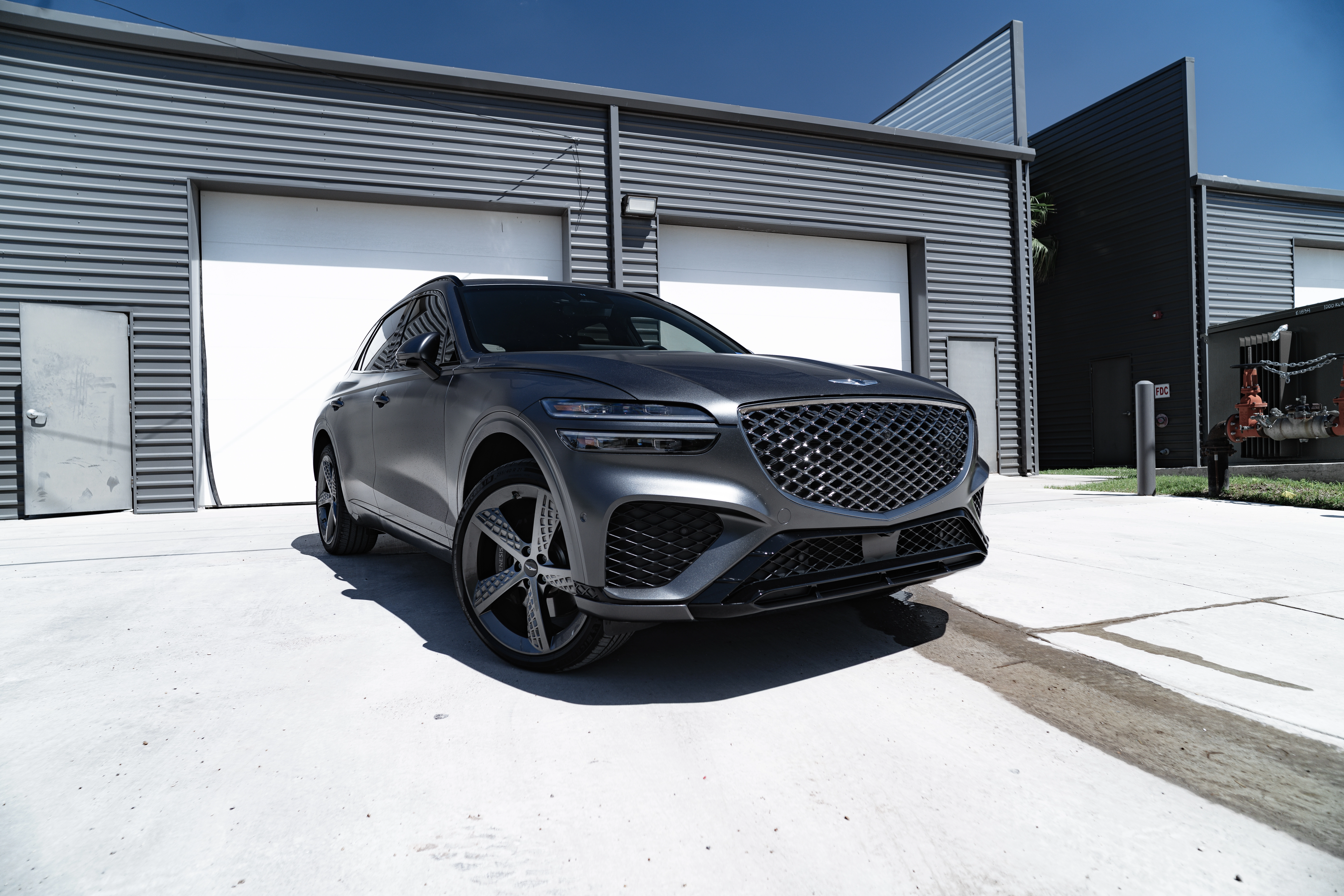 Gray Genesis GV70 parked outside a garage