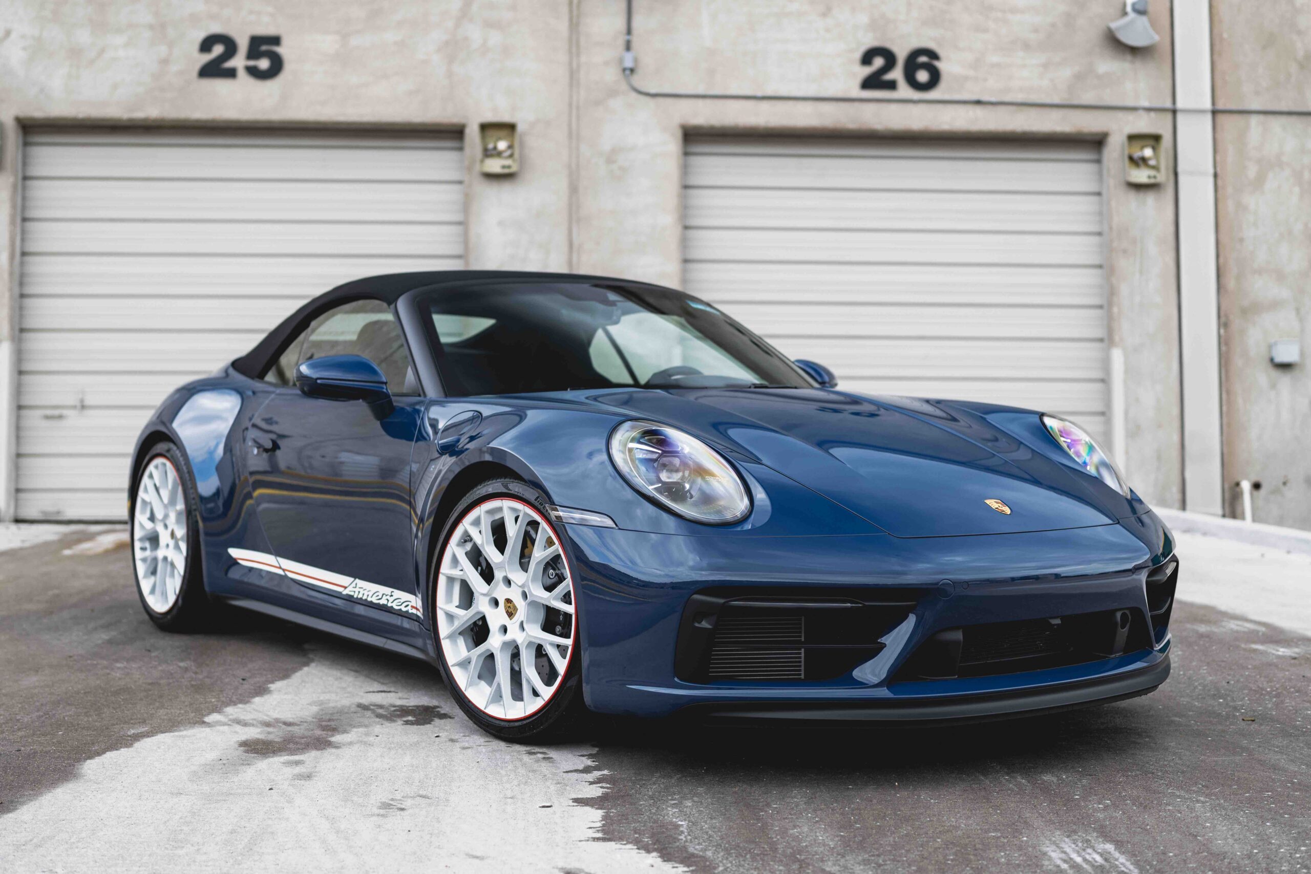 blue Porsche 911 parked outside garage
