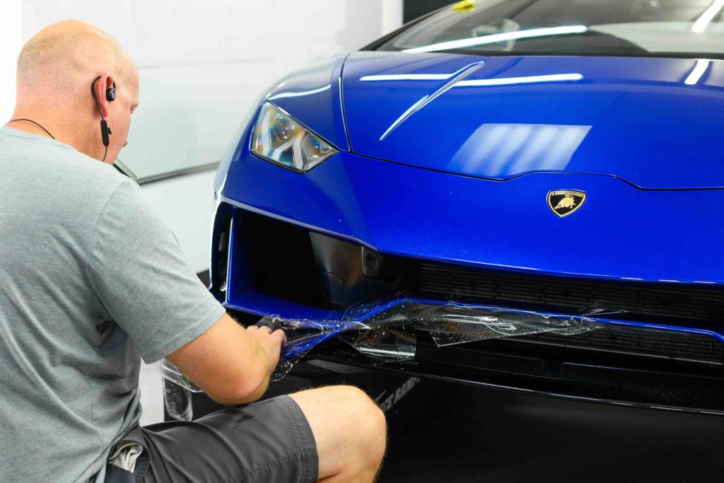 paint protection film being applied to a blue car