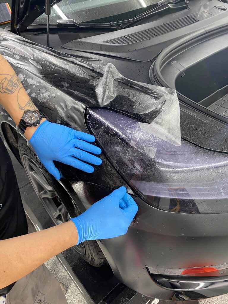 Sun Stoppers workers applying paint protection film to a car